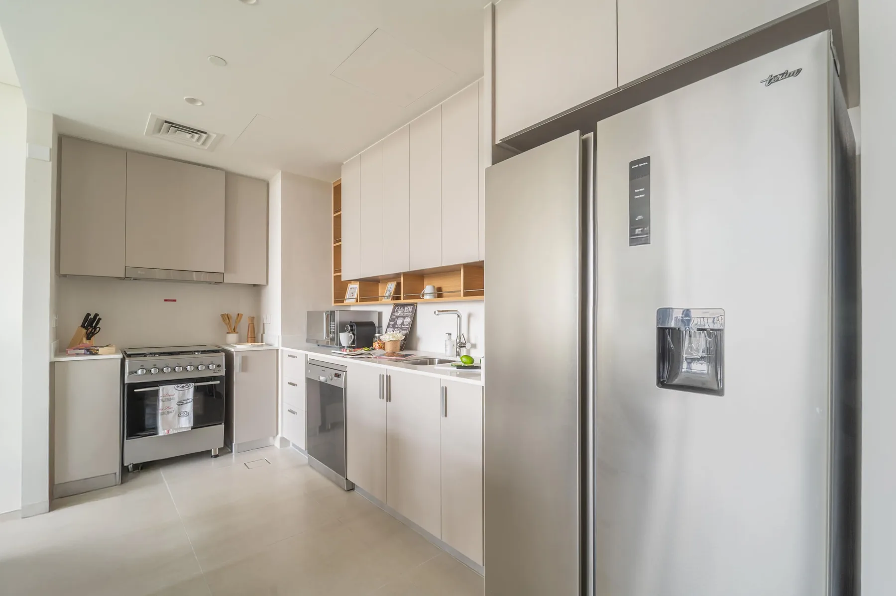 Una cocina moderna y luminosa con gabinetes blancos, encimeras y electrodomésticos de acero inoxidable.