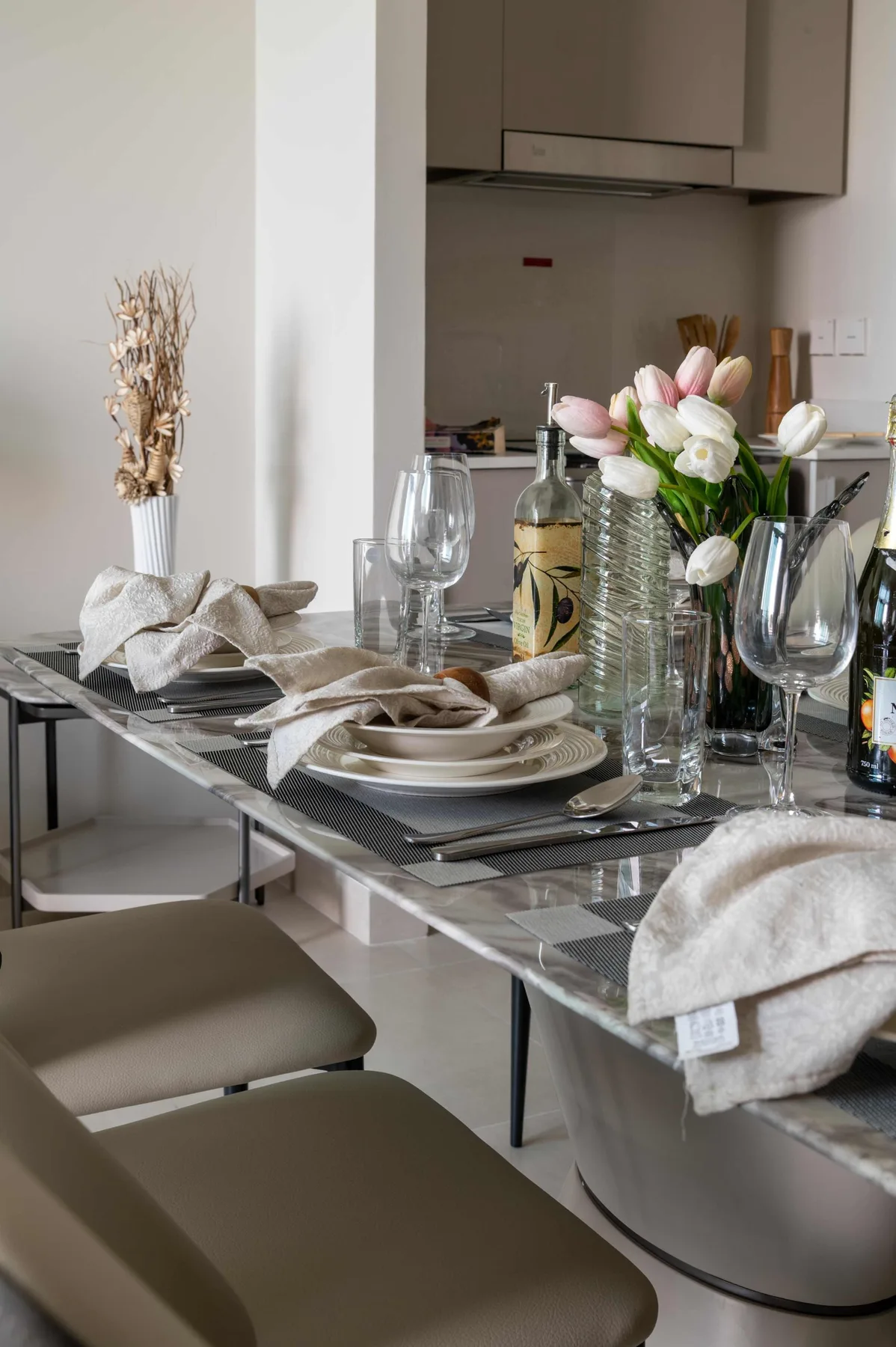 Una mesa de comedor está puesta con platos, cristalería, servilletas dobladas y flores.