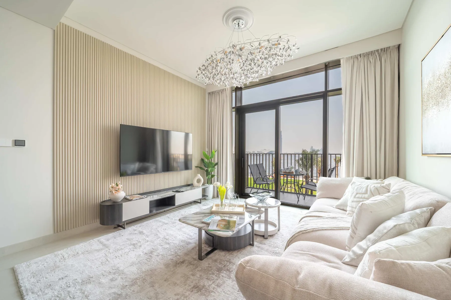 Sala de estar luminosa con asientos, mesas bajas y puertas de vidrio.