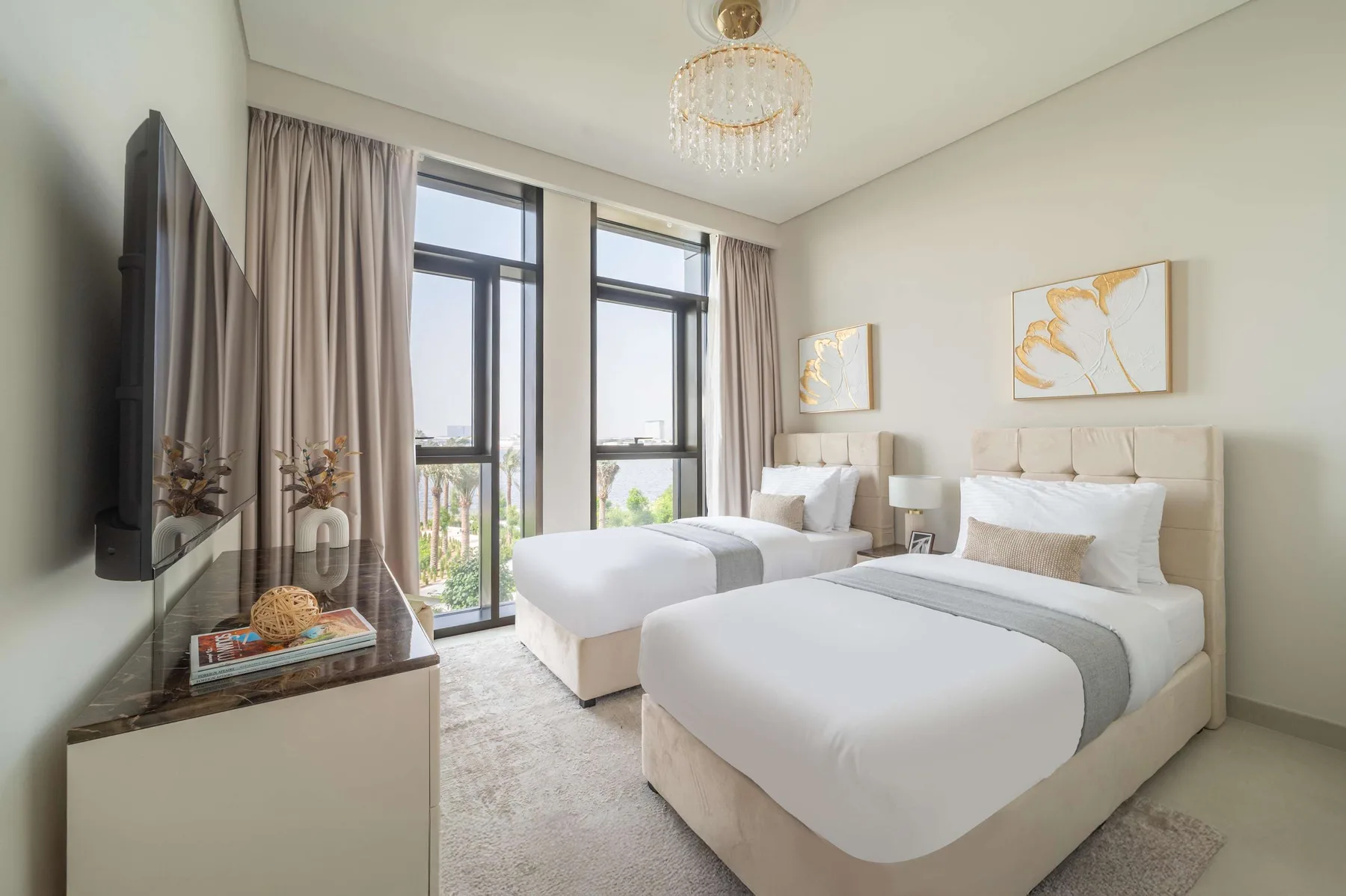 Un dormitorio luminoso con dos camas y ventanas altas.