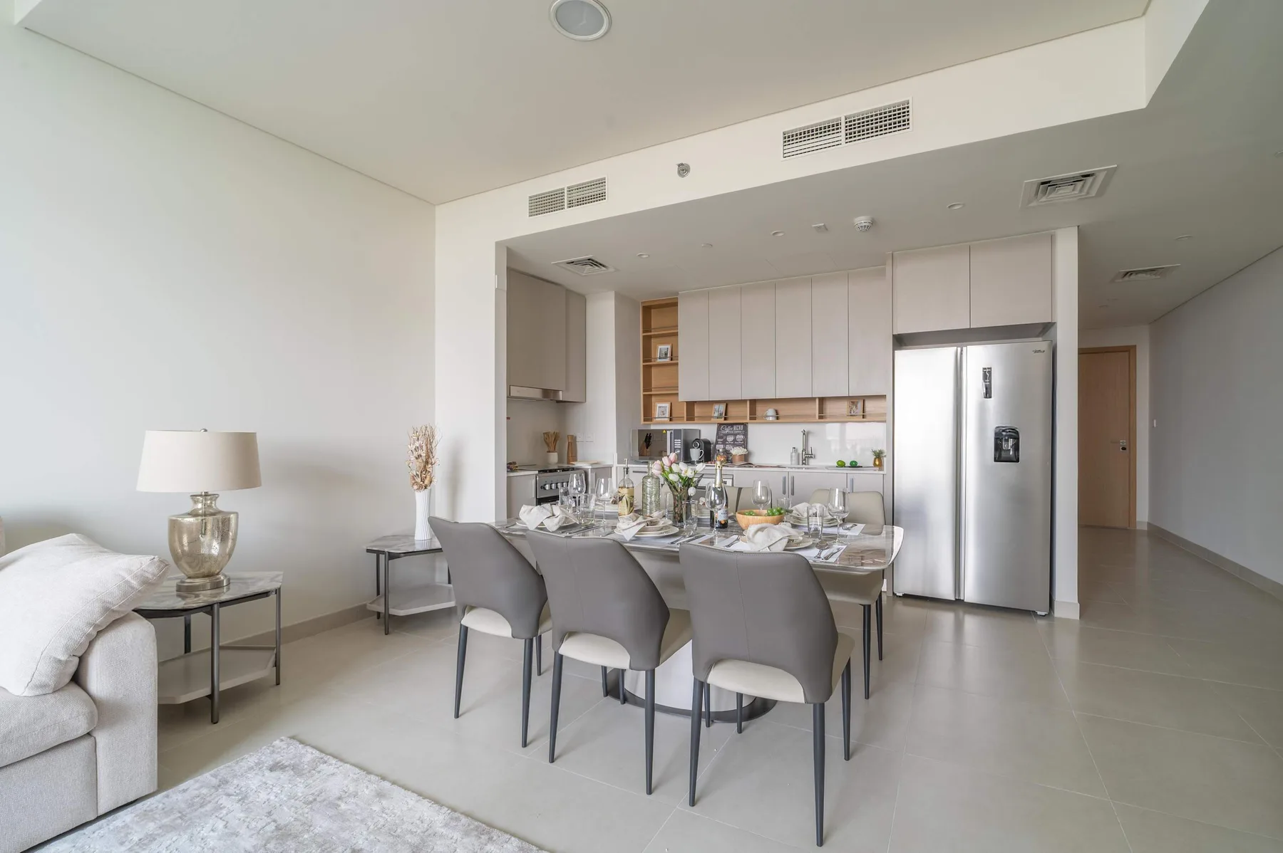 Un comedor luminoso con mesa y asientos junto a una cocina abierta.