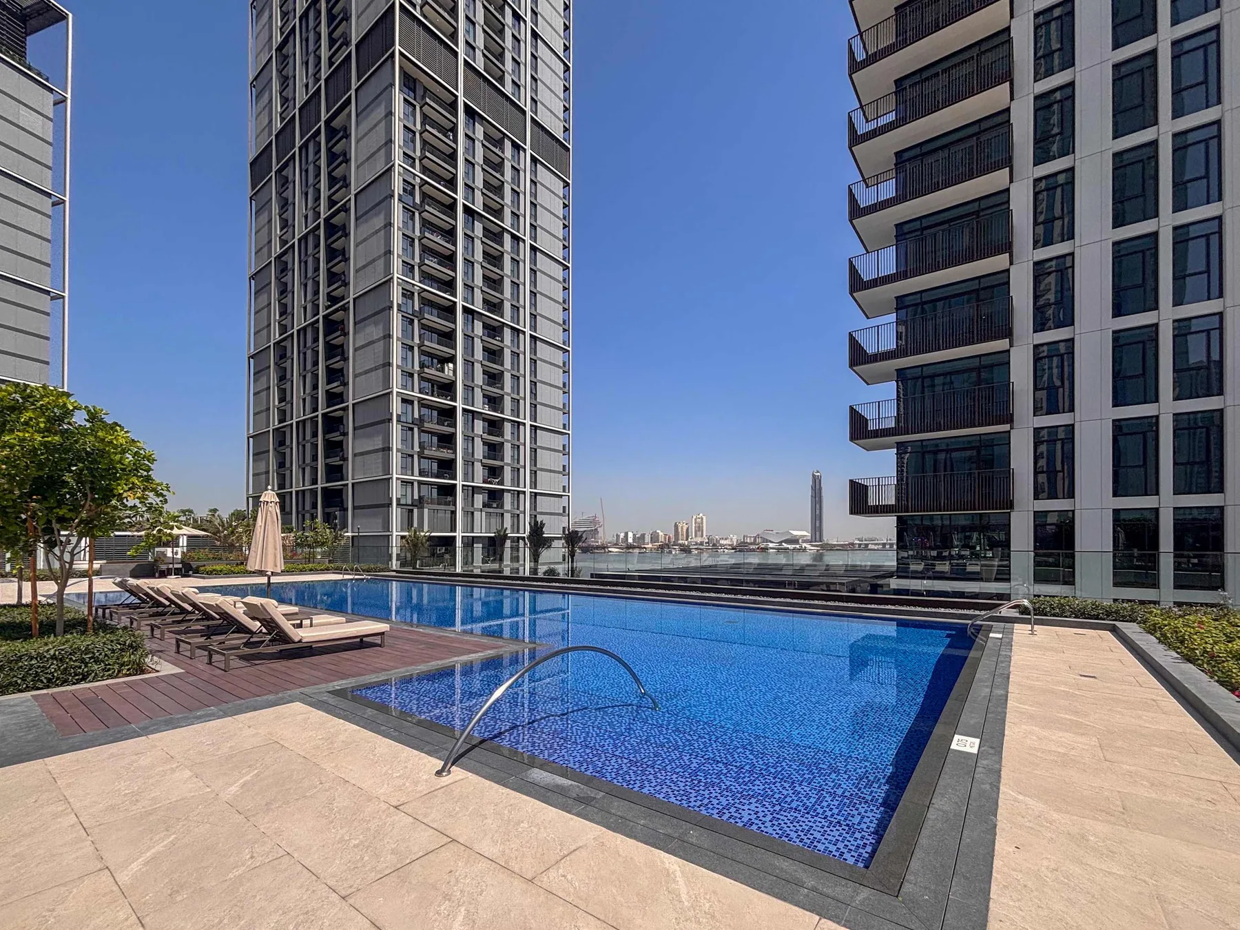 Una piscina al aire libre se encuentra entre edificios modernos de gran altura.
