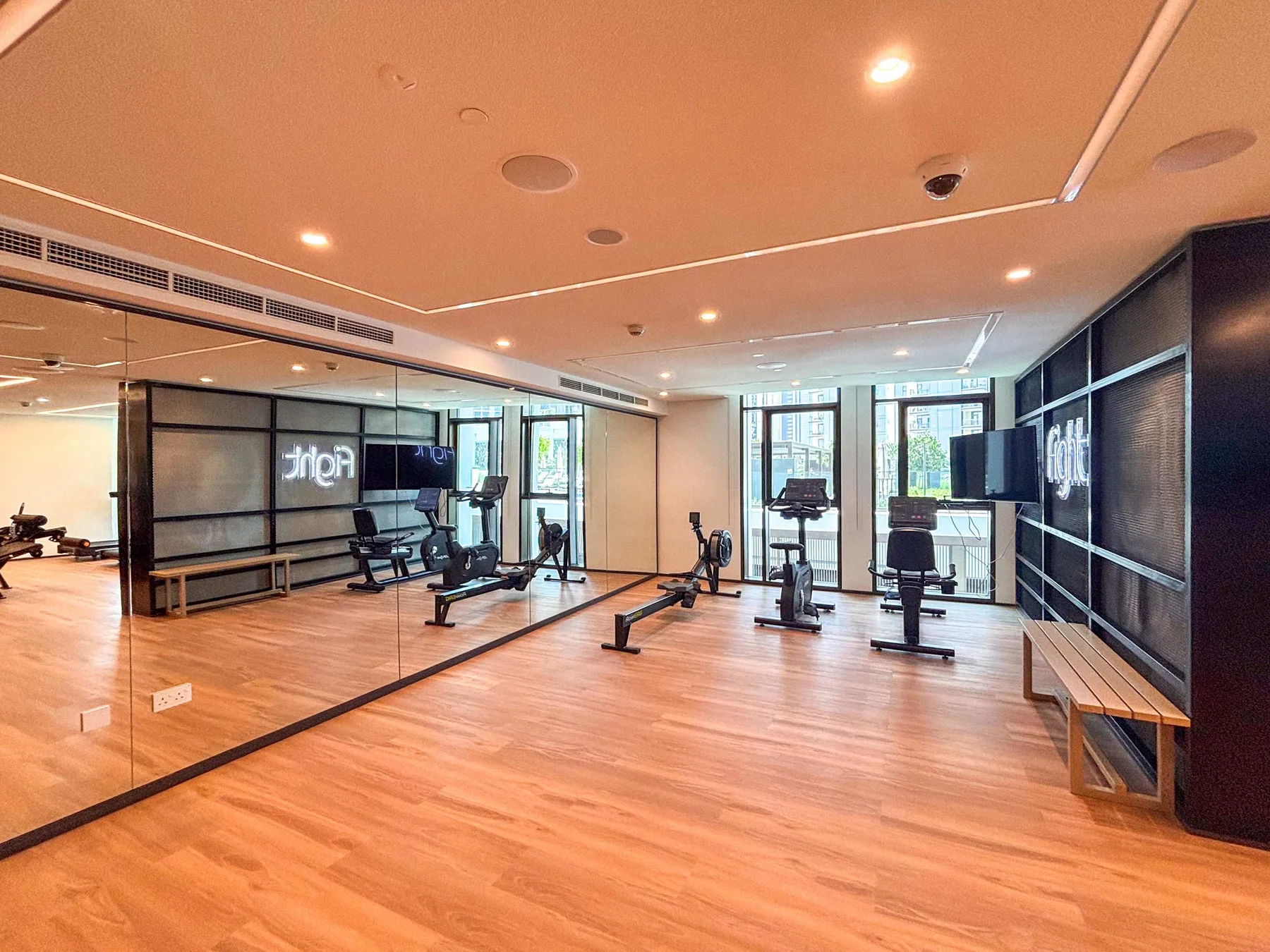Una sala de ejercicio con equipos de entrenamiento y paredes con espejos.