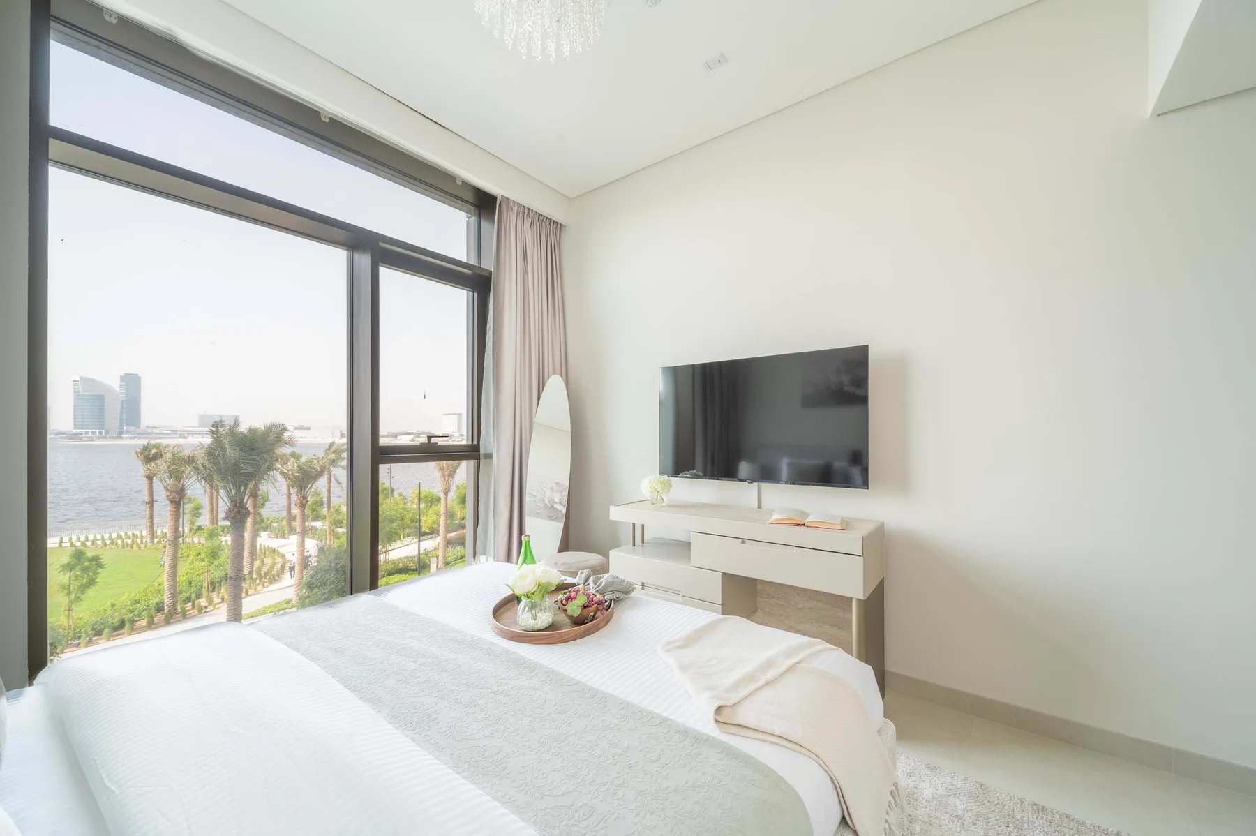 Un dormitorio luminoso con una ventana grande y un televisor en la pared.
