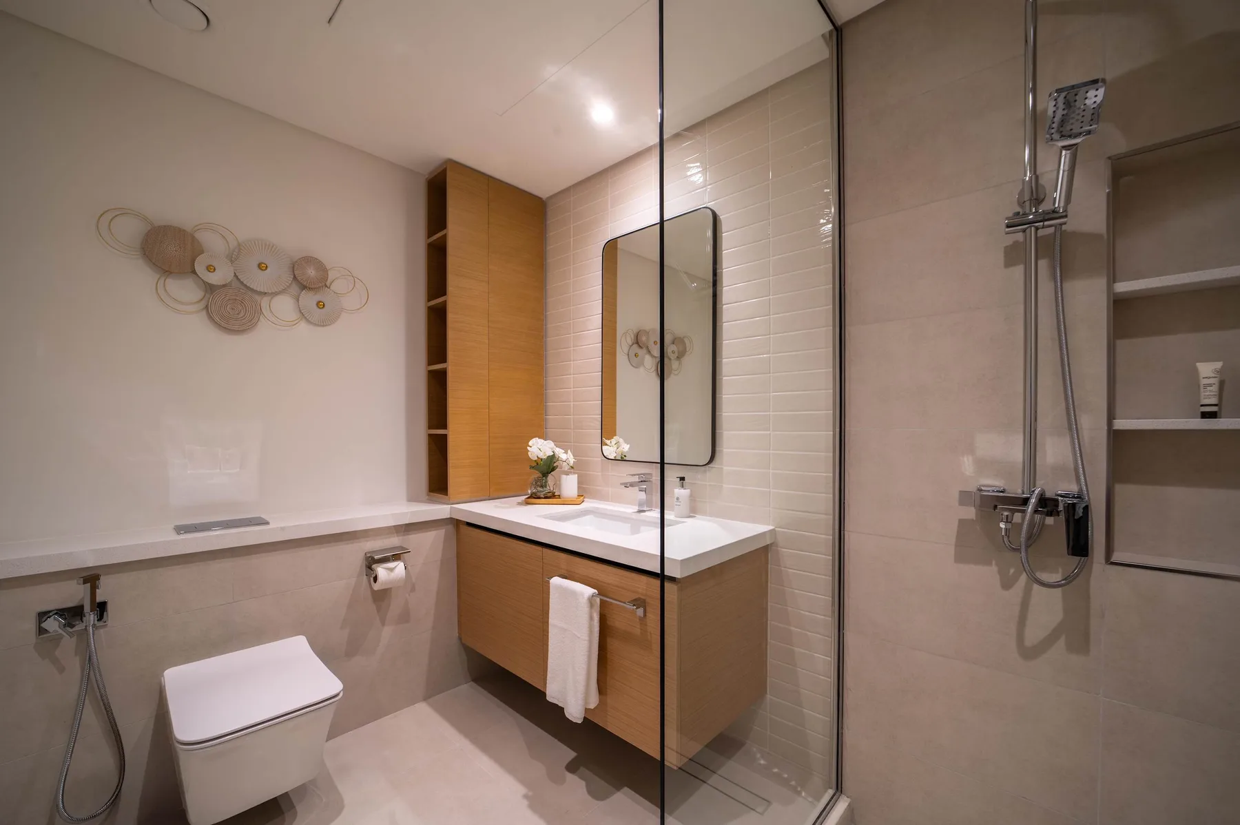 Un baño moderno con lavabo, espejo, inodoro y ducha de vidrio.