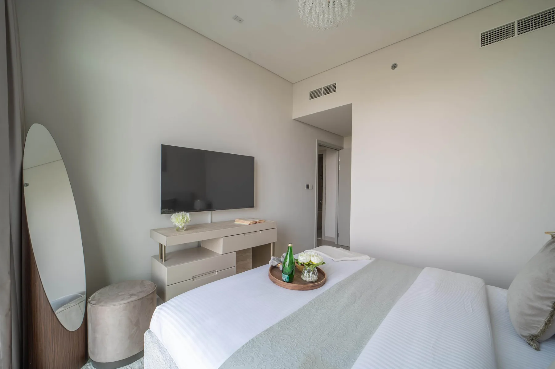 Un dormitorio luminoso con cama, televisor y espejo de cuerpo entero.