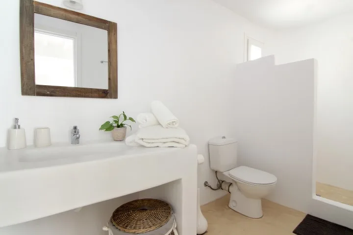 A bright bathroom with a wide sink, mirror, and toilet.