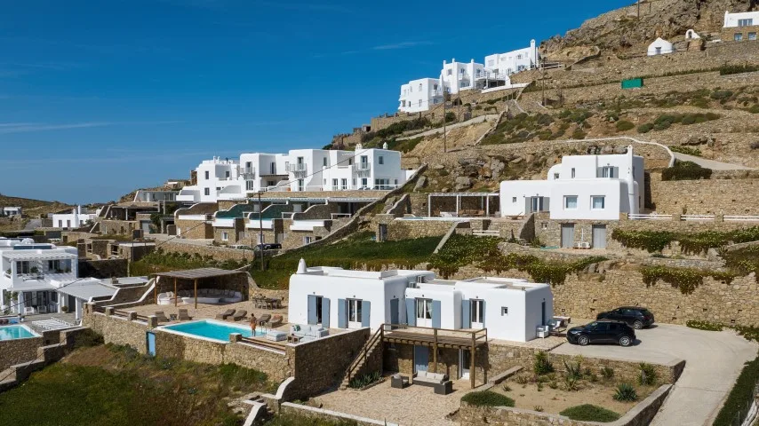 White buildings and turquoise pools dot a dry hillside.