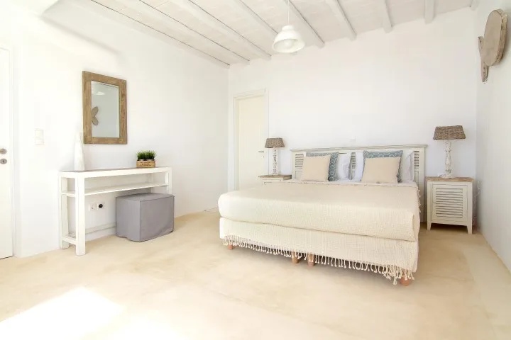 A bright bedroom with a bed, bedside tables, and a desk.