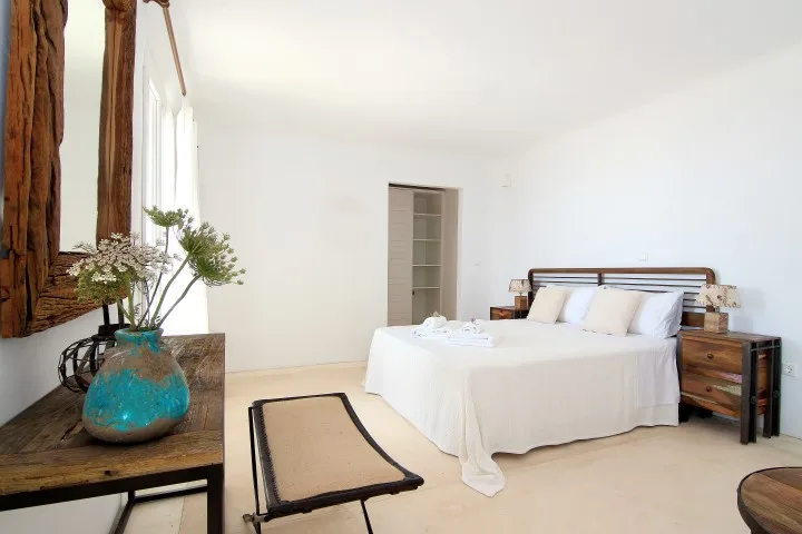 A bright bedroom with a white bed and wooden bedside tables.