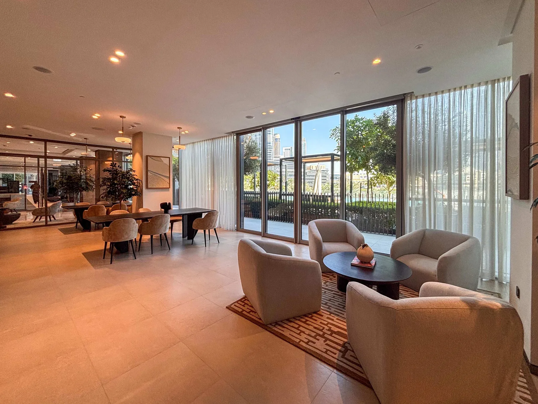 Una sala luminosa con asientos alrededor de una mesa baja junto a ventanales.