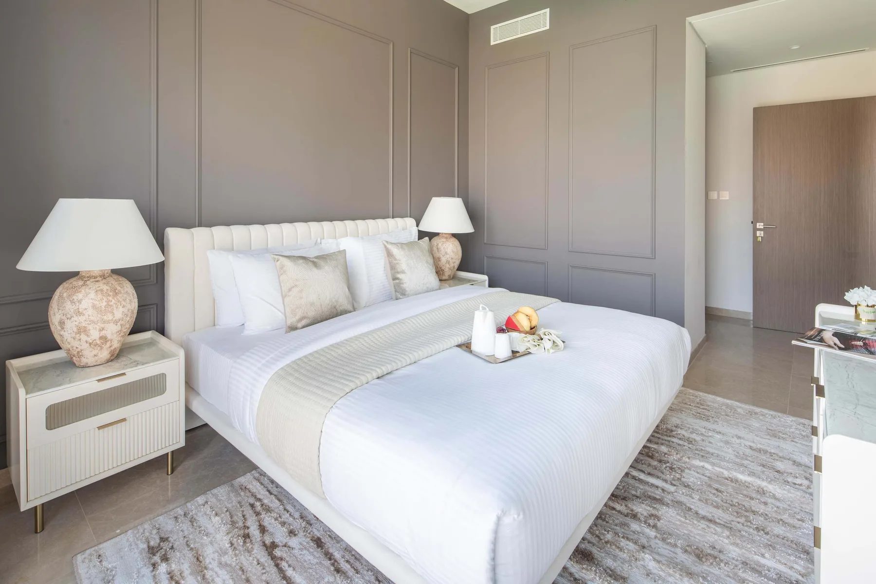 Un dormitorio con una cama grande, mesitas de noche y una alfombra clara.