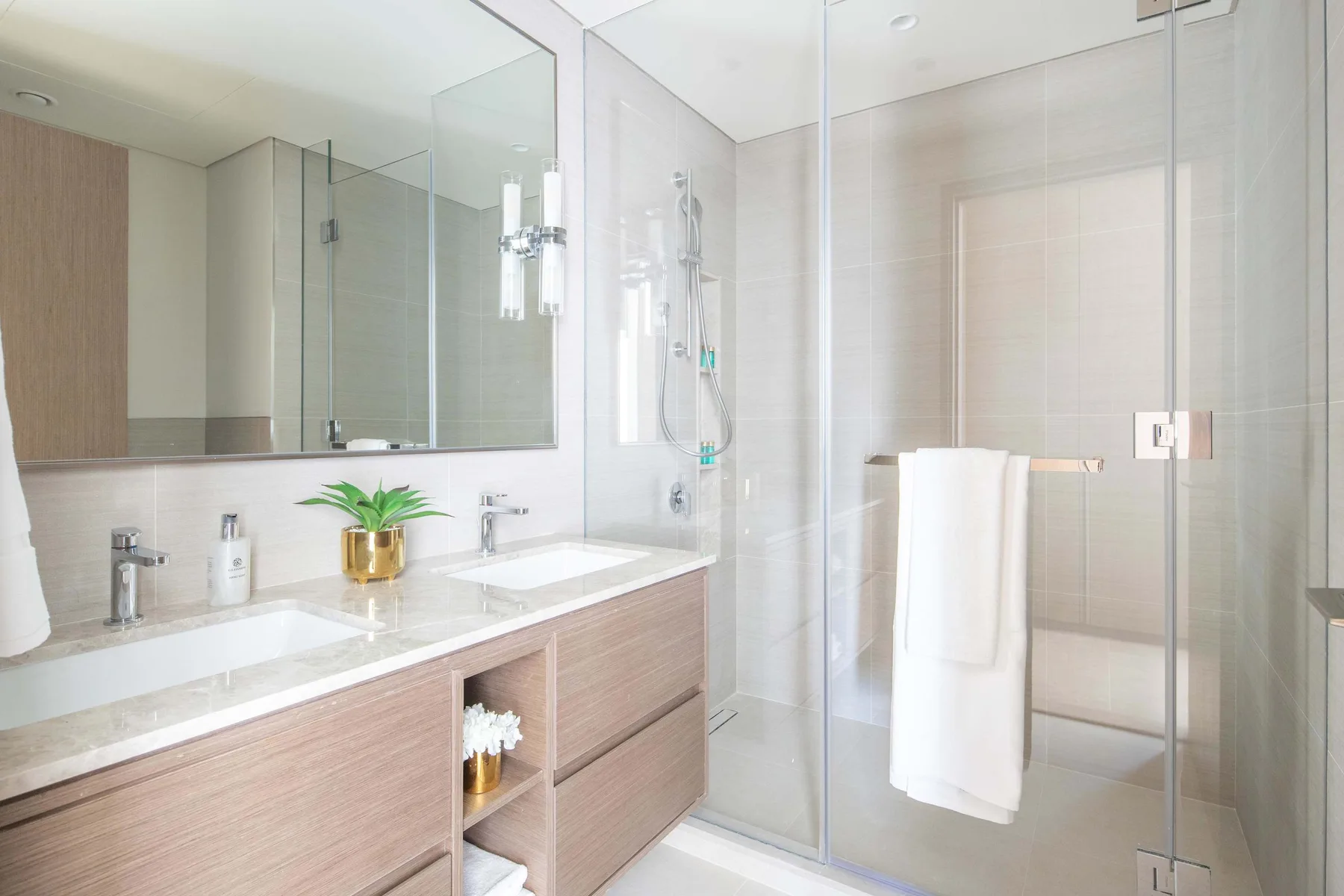 Un baño luminoso con un tocador largo y una ducha de cristal.