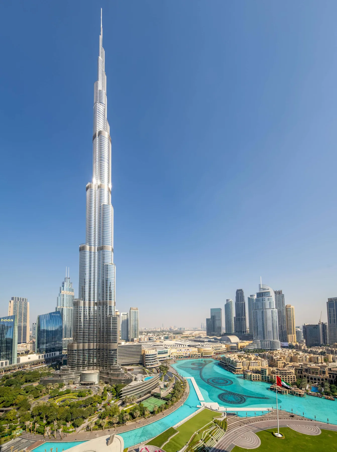 Un horizonte urbano con una torre muy alta junto a una zona costera turquesa.