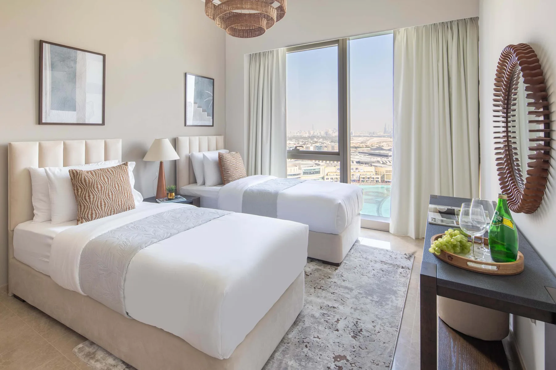 Un dormitorio luminoso con dos camas junto a una gran ventana con vistas a la ciudad.
