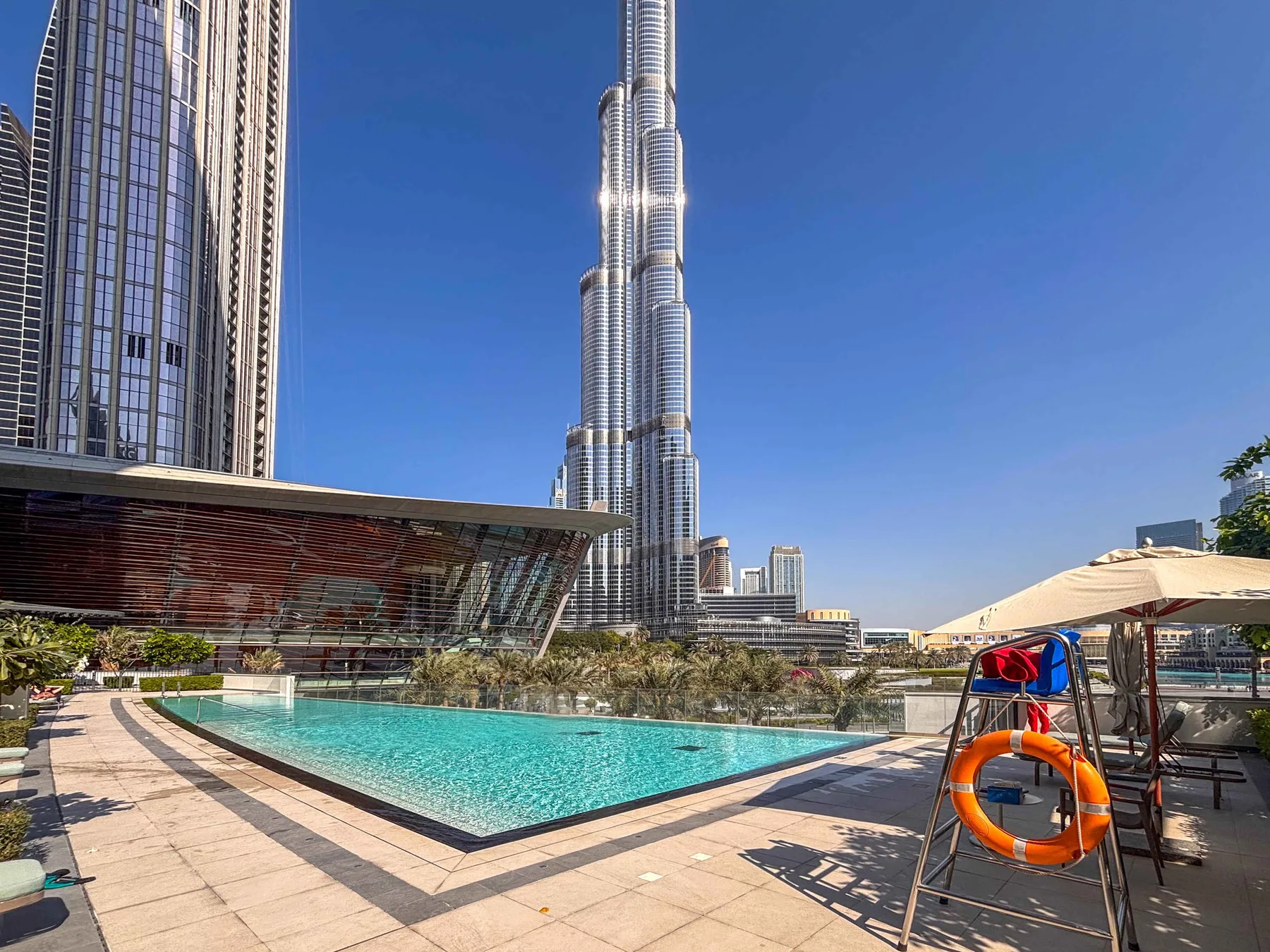 Una piscina al aire libre y una terraza pavimentada están junto a altos edificios urbanos.