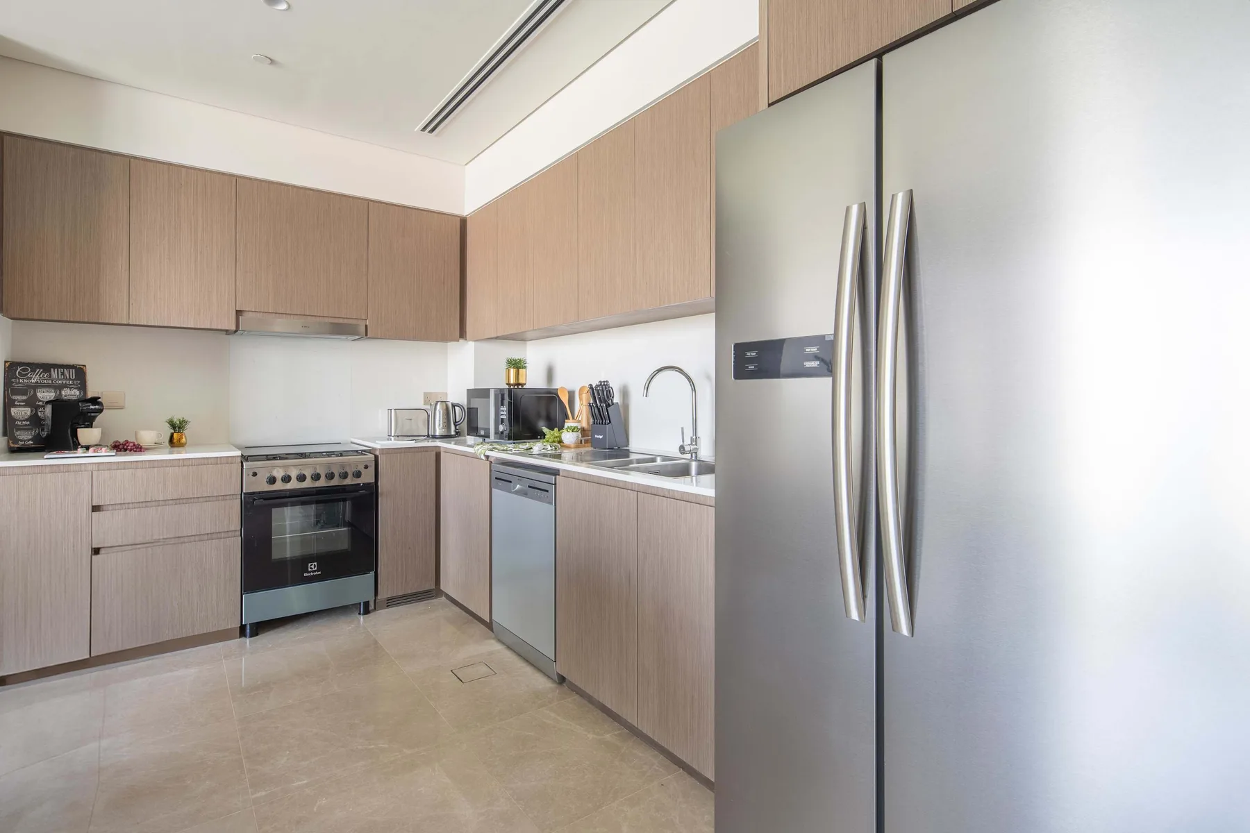 Una cocina moderna con armarios de madera, electrodomésticos de acero inoxidable y suelo de baldosas.
