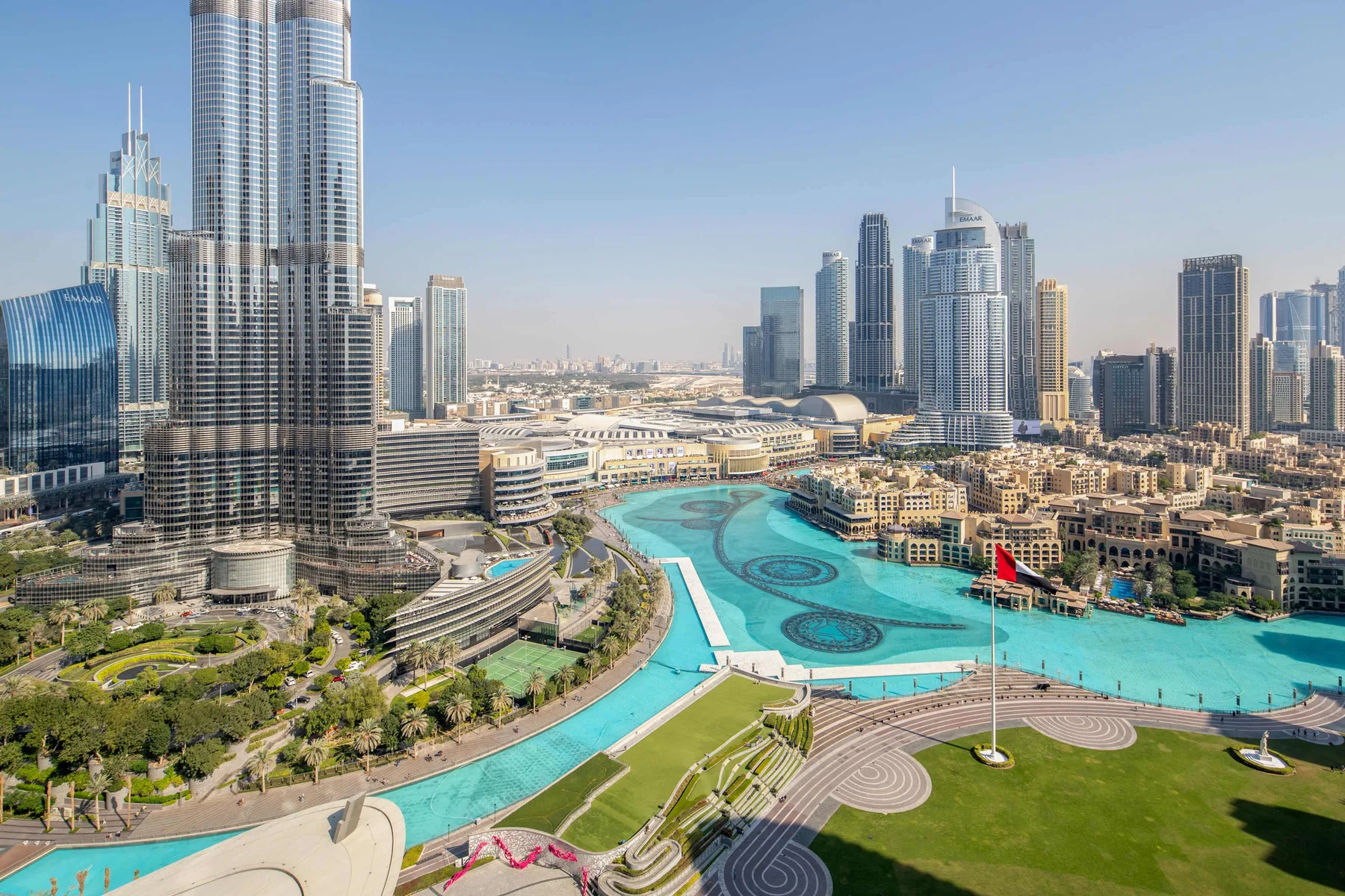 Un horizonte urbano se alza sobre una piscina turquesa y jardines.