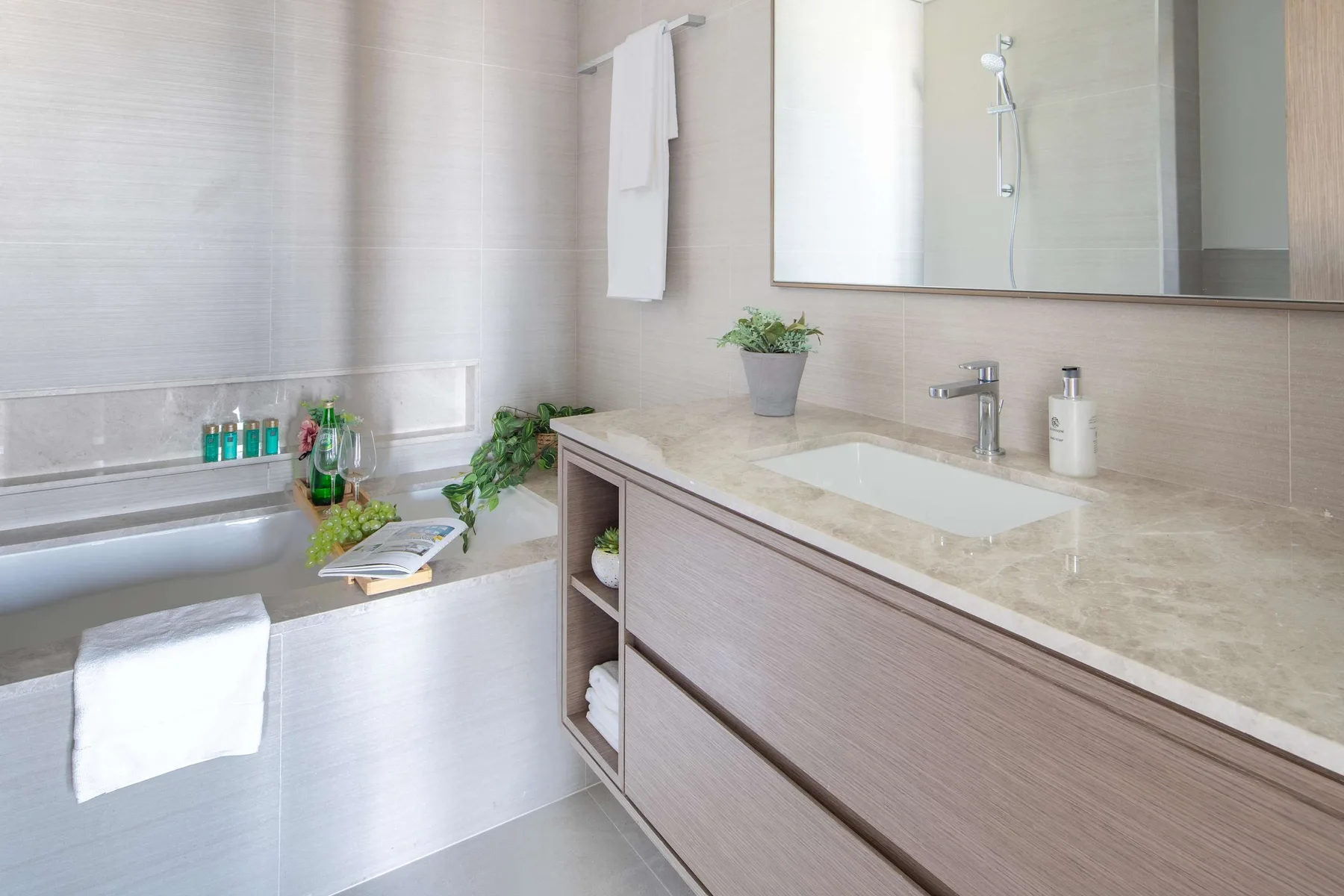 Un baño luminoso con bañera y un largo tocador con lavabo.