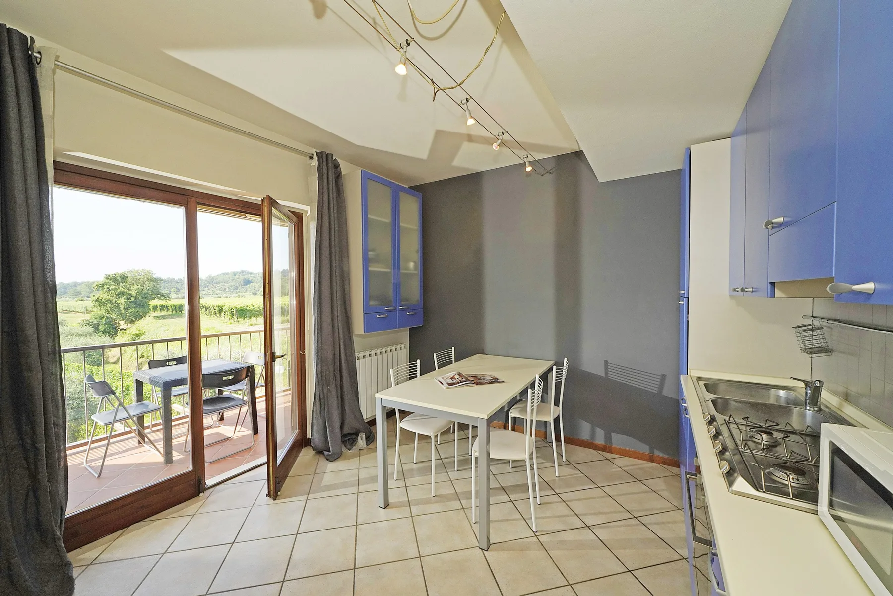 A dining area and kitchen with a table beside glass doors opening onto a balcony.