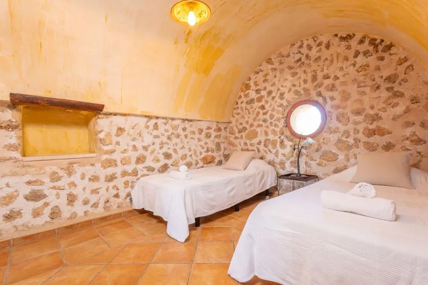 Un dormitorio con dos camas y paredes de piedra.