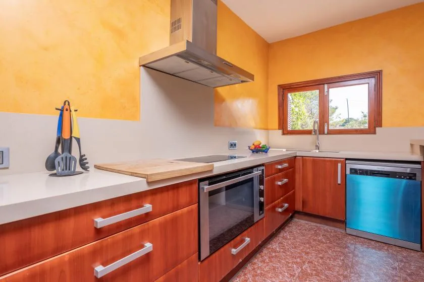 Una cocina luminosa con gabinetes de madera, una encimera y una ventana sobre el fregadero.