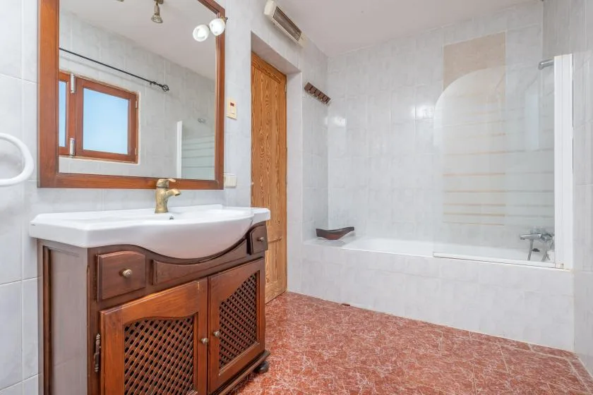 Un baño con un mueble de lavabo y una bañera junto a la pared alicatada.