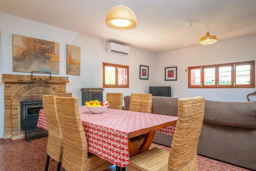 Un comedor con un mantel estampado, asientos de mimbre y una chimenea de ladrillo.