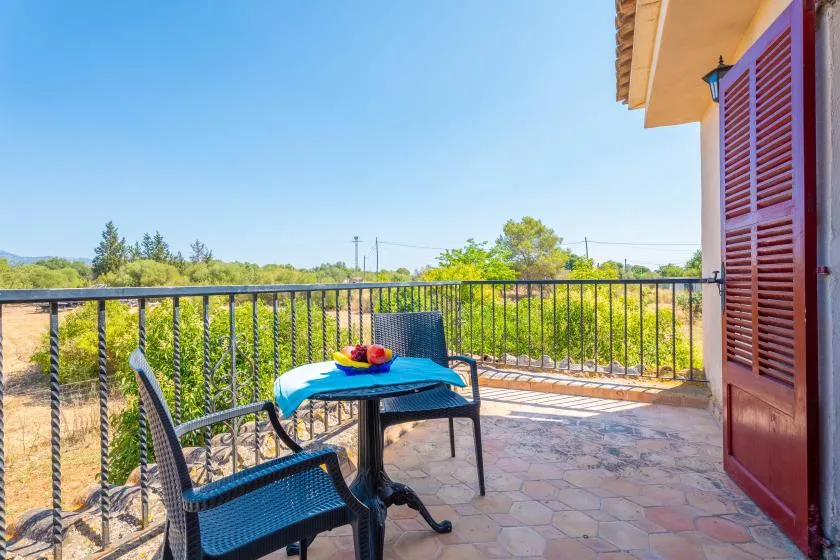 Una terraza soleada al aire libre con asientos, una mesa y vistas a la vegetación.