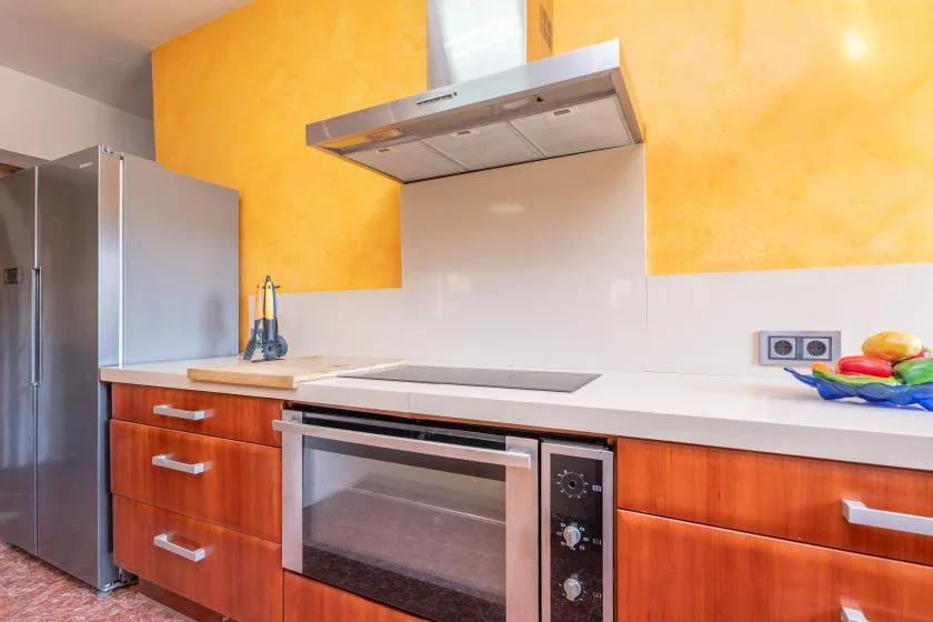 Una cocina con horno empotrado, placa de cocción y refrigerador de acero inoxidable.