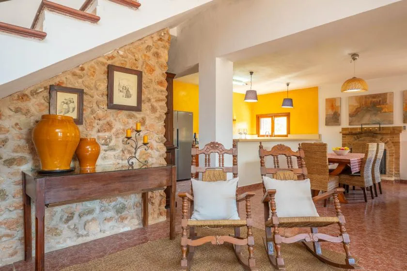 Una zona rústica de estar y comedor con asientos de madera y una pared de piedra.