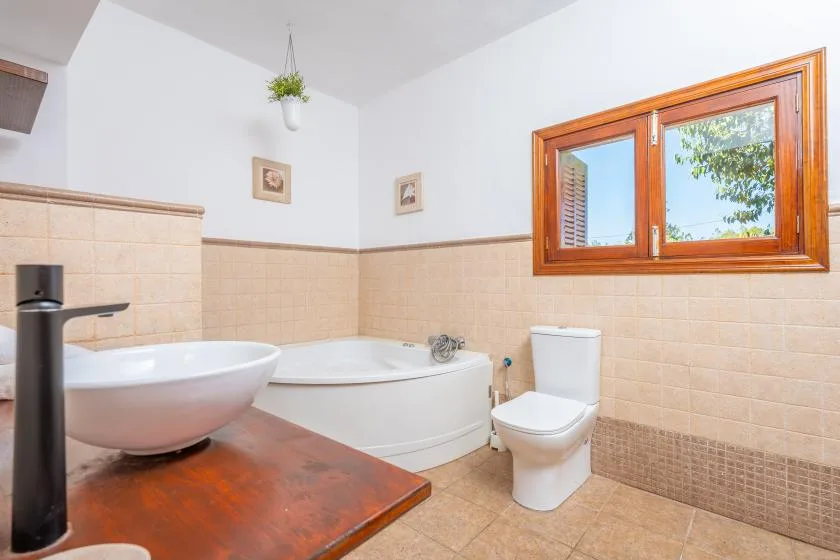 Un baño con bañera, inodoro y ventana.