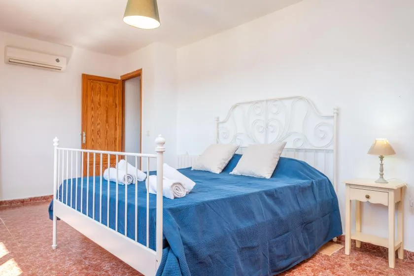 Un dormitorio con una cama vestida con ropa de cama azul y una mesita de noche.
