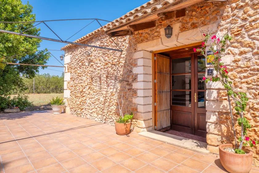 La entrada de un edificio de piedra da a un patio soleado con macetas.