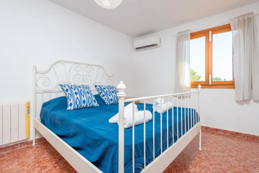 Un dormitorio con una cama cubierta de azul junto a una ventana con cortinas.