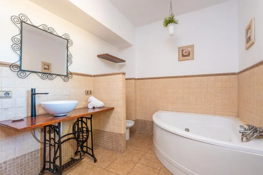 Un baño con una bañera grande, lavabo y espejo decorativo.