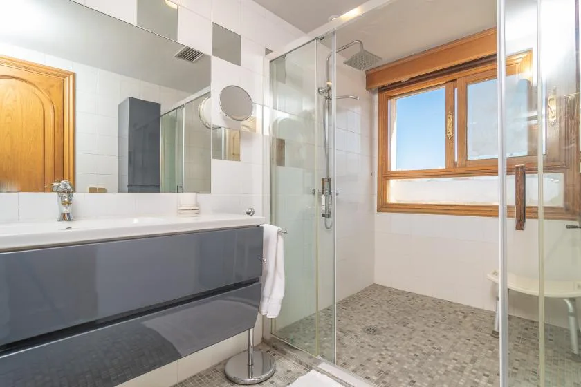 A bathroom with a bathtub, glass shower, and large window.