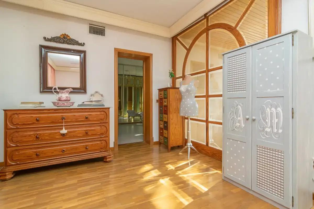 A furnished room with wooden flooring, a dresser, and a wardrobe.