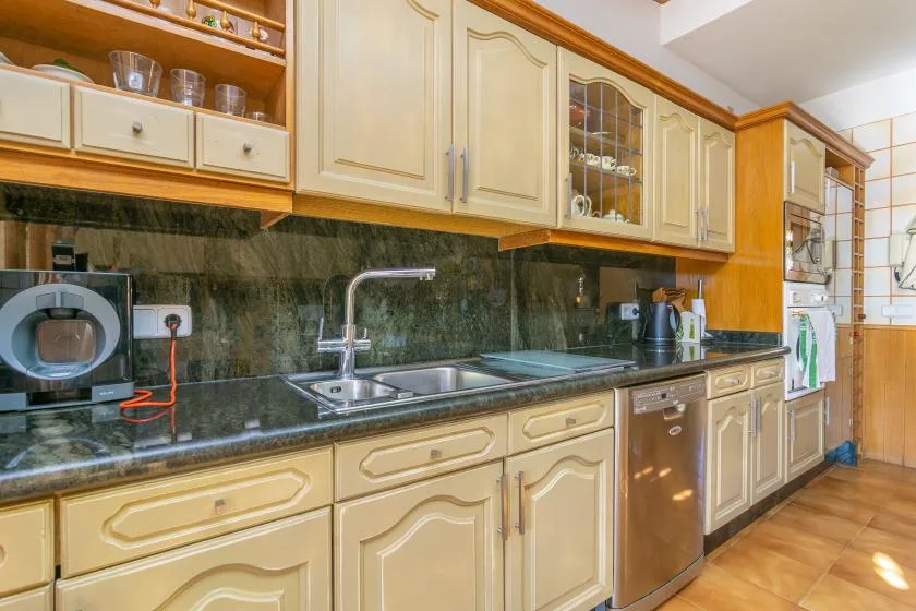 A kitchen with cream cabinets, dark countertops, and a sink.