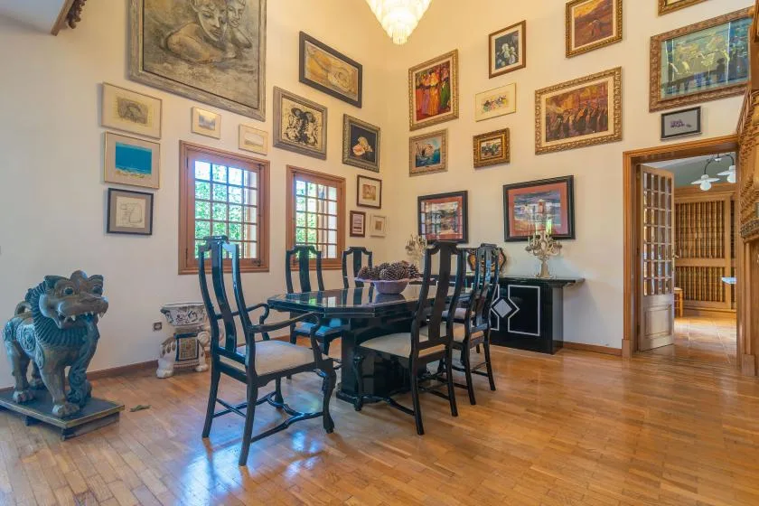 A dining room with a table and chairs beneath walls covered in framed artwork.