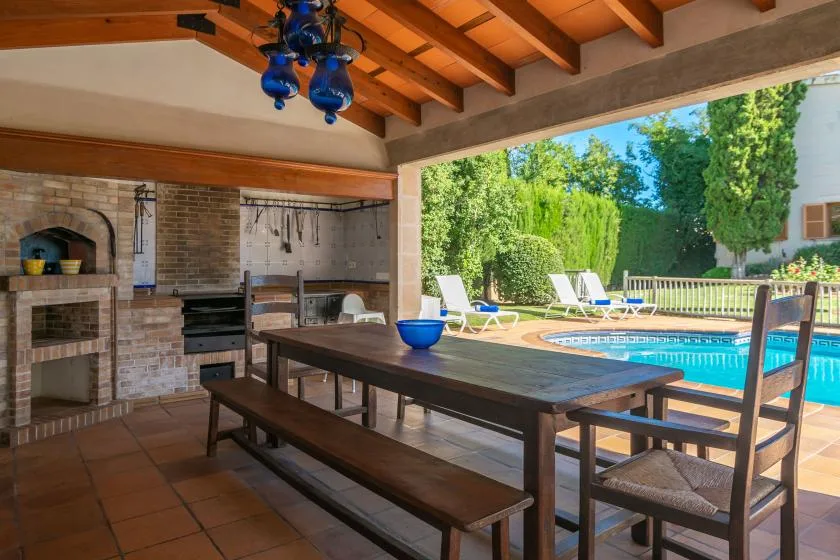 A covered outdoor dining area opens onto a pool and garden.