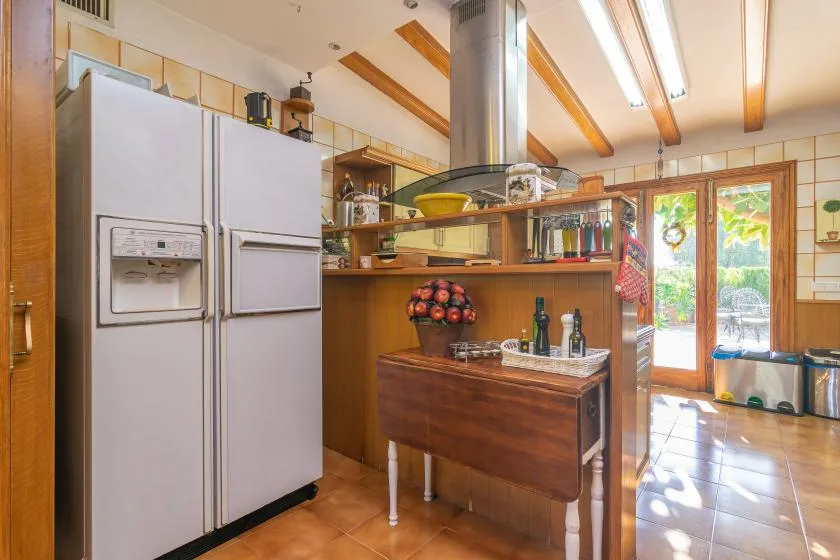 A kitchen with a wooden island and glass doors opening to a patio.