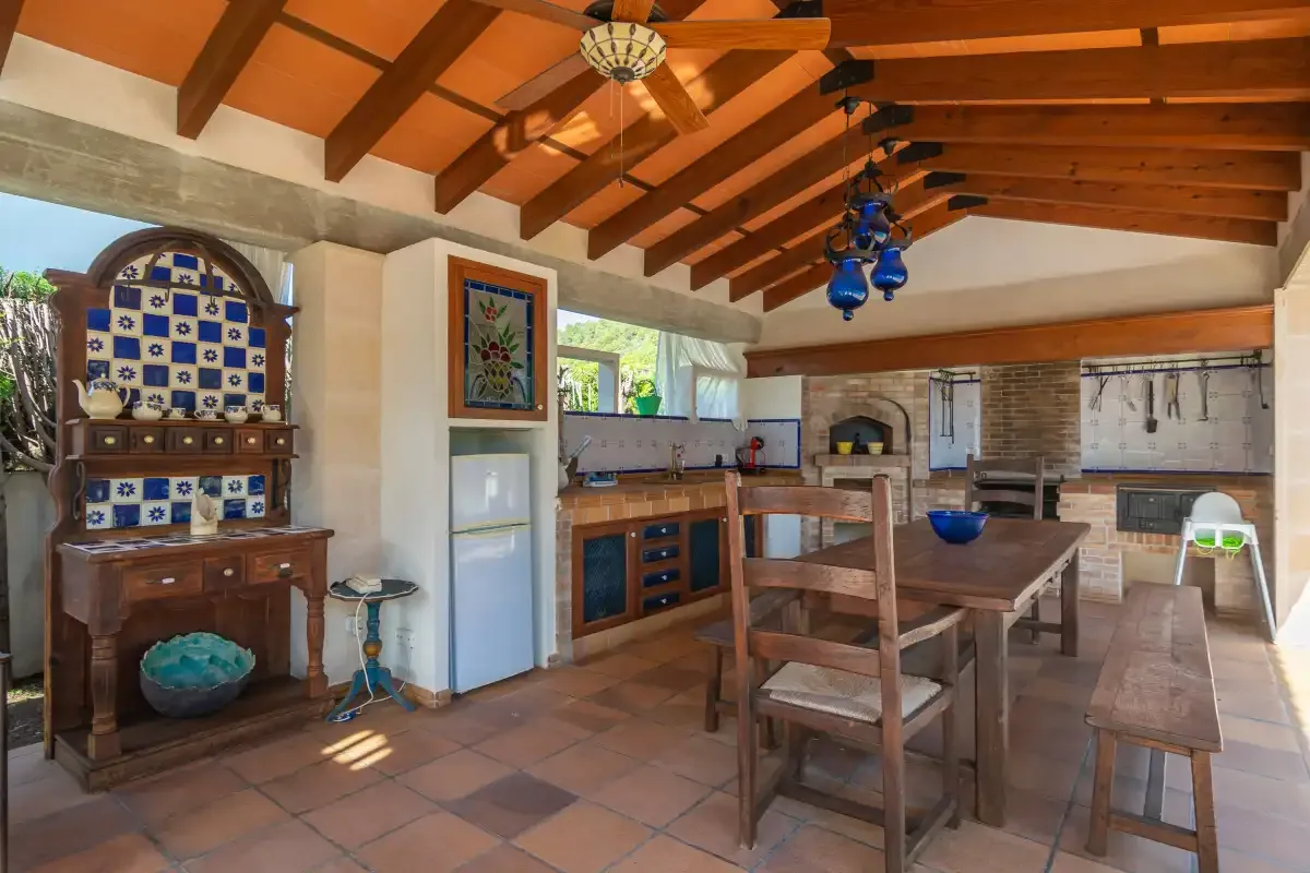A rustic kitchen and dining area with exposed wooden ceiling beams.