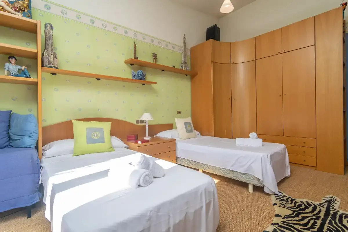 A bedroom with two beds and wooden wardrobes.