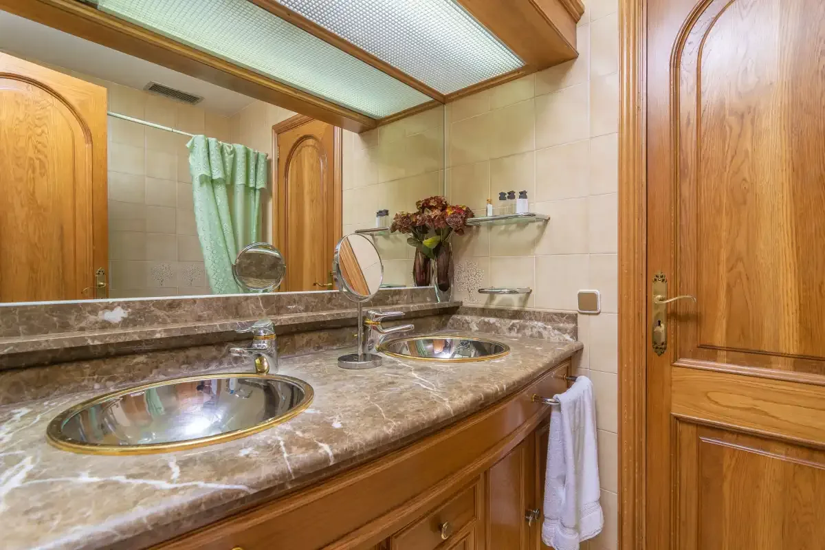 A bathroom vanity with two sinks, a large mirror, and wooden cabinetry.