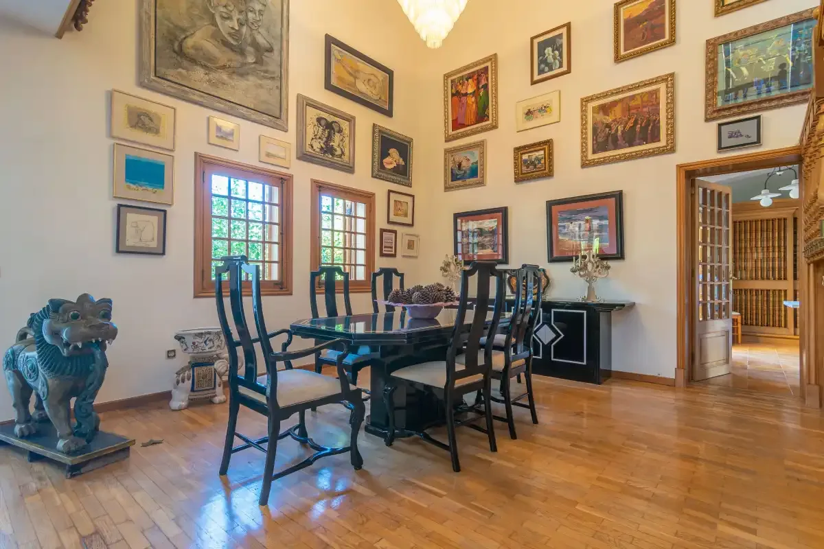 A dining room with a table and chairs beneath walls covered in framed artwork.