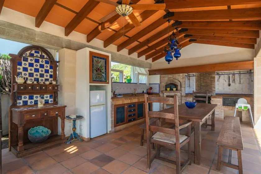 A rustic kitchen and dining area with a wooden table beneath exposed ceiling beams.