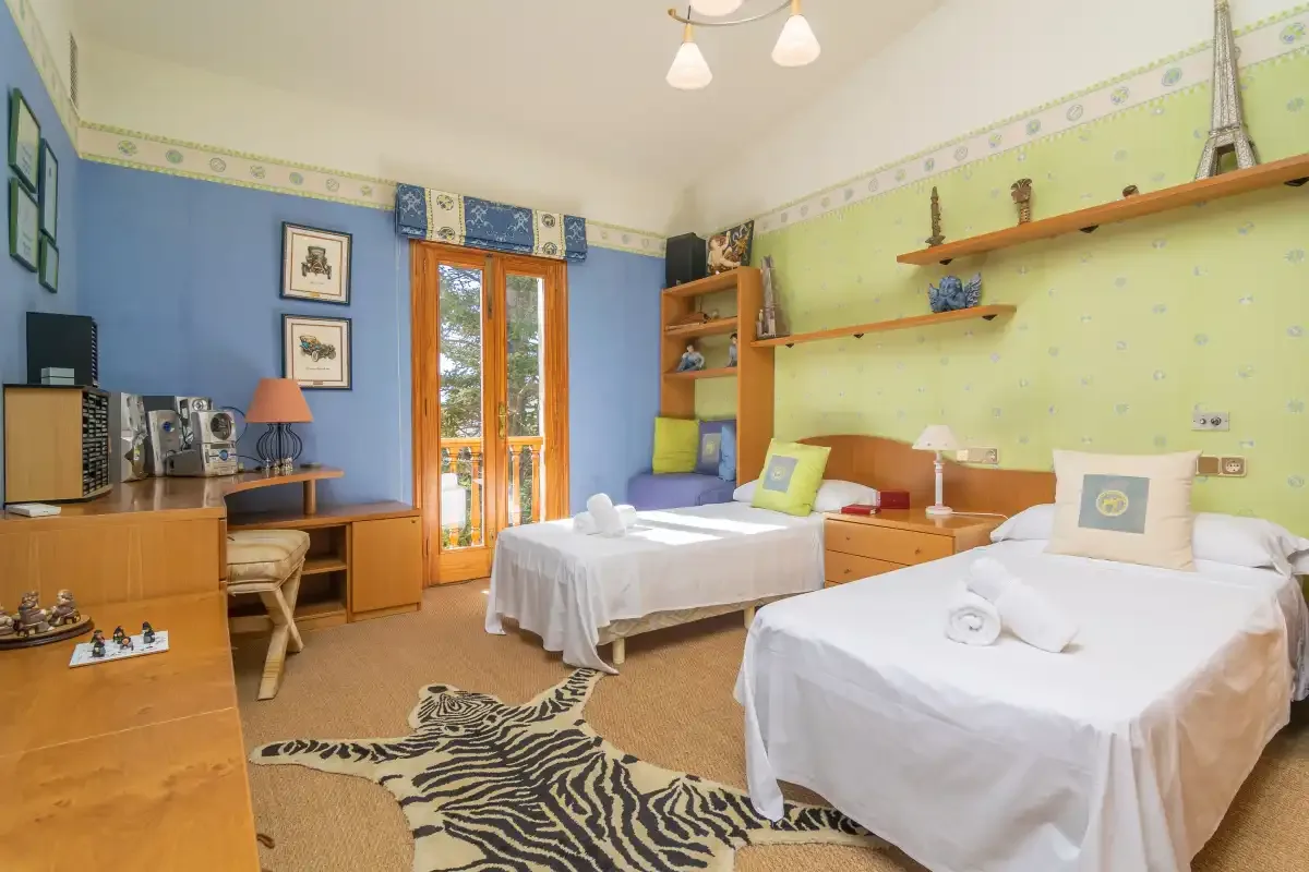 A bedroom with two single beds, wooden shelving, and a small desk.