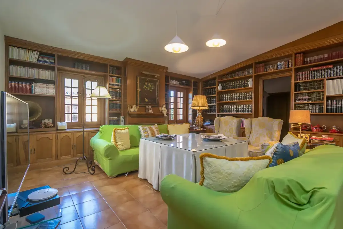 A book-lined living room with seating arranged around a table.