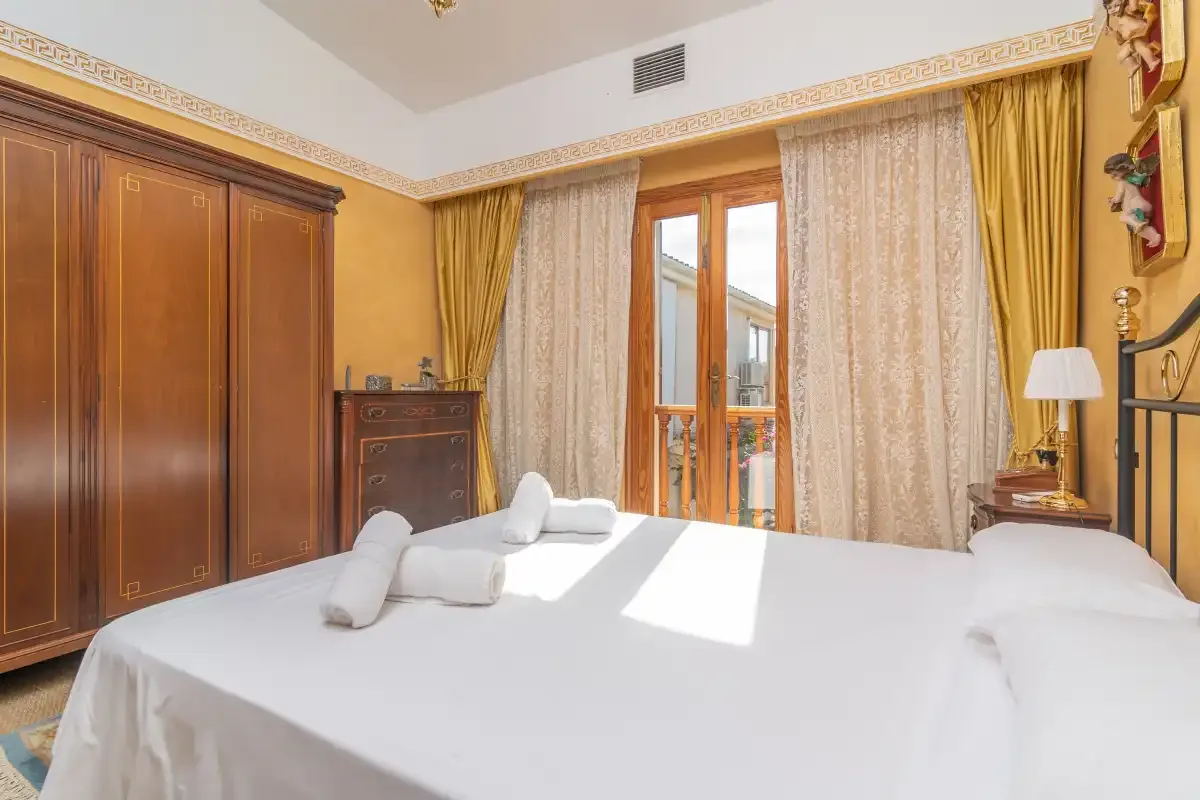 A bedroom with a neatly made bed and wooden wardrobes.